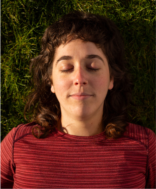 Yin Yoga instructor laying on grass with her eyes closed